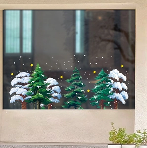 Close-up of snowy pine trees and yellow star static window stickers on a dark glass pane