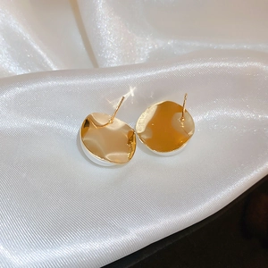 Detailed close-up of retro gold irregular round stud earrings on white silk fabric
