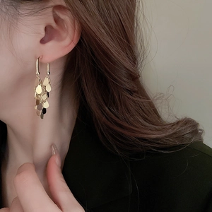 Detail of elegant gold-plated layered sequin tassel earrings worn by a model