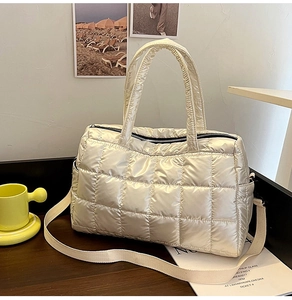 Detailed shot of beige quilted puffer tote bag with detachable strap on a wooden desk