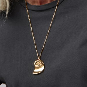 Close-up of golden nautilus shell pendant necklace worn on a dark t-shirt background
