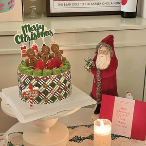 Close-up of Christmas cake with gingerbread men, red bow, and Merry Christmas gold topper