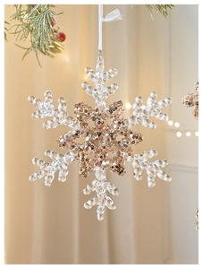 Close-up of acrylic snowflake ornament with gold sequins and textured transparent edges