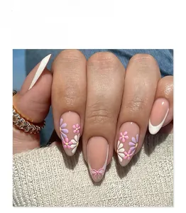 Dettaglio di unghie finte a mandorla corte con French bianco e motivi floreali viola