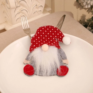 Porte-couverts gnome avec bonnet rouge à pois et barbe blanche sur une assiette blanche