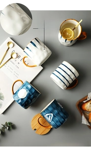 Flat lay of Nordic ceramic mugs with blue textures, gold handles, and wooden lids
