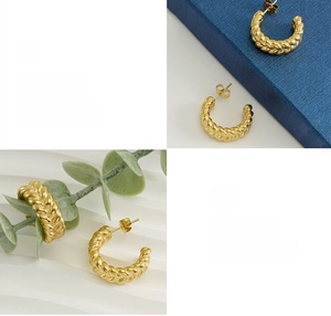 Detailed view of polished 18k gold twist C-shape earrings with a high-shine finish