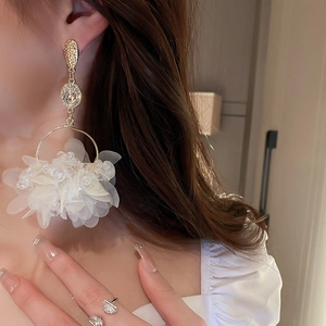 Elegant fabric flower earrings with white pearls and gold accents worn by a model