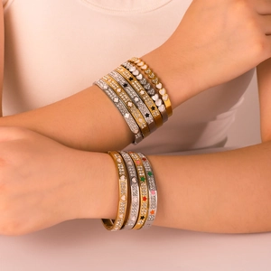 Stack of 18K gold and silver stainless steel bangles with colorful enamel stars and crystals