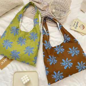 Close-up of blue floral print canvas tote bags in green and brown displayed on white bedding
