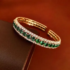 Elegant gold-plated open bangle featuring emerald green crystals and white zircon accents