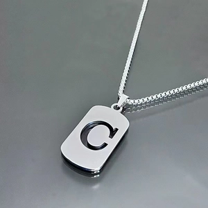 Detailed close-up of a silver stainless steel necklace with a hollow letter C pendant
