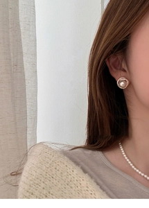 Close-up of elegant gold pearl stud earrings with shimmering zircon halo on a model