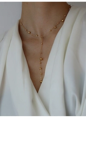 Close-up of minimalist 18k gold plated Y-shaped necklace with polished beads on model