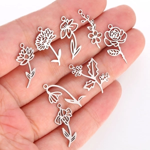 Detailed view of eight assorted silver stainless steel floral charms held in a hand