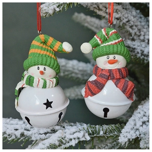 Close-up of snowman bell ornaments hanging on snowy pine branches for Christmas decor
