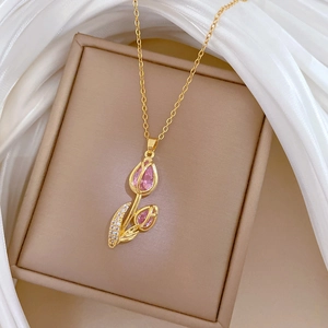 Close-up of golden tulip necklace with pink crystal and diamonds on white silk