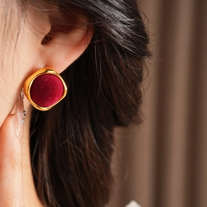 Vue macro de boucles d'oreilles géométriques en velours rouge et bordure dorée