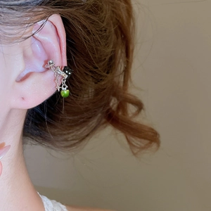 Close-up of silver star ear cuff with green beads and black square charm on model
