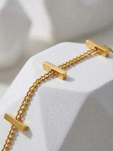 Macro shot of 18k gold plated stainless steel bar chain bracelet on stone