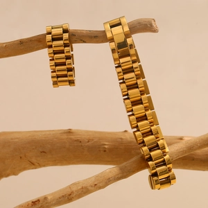 Detail of 18K gold plated stainless steel watch-link bracelets on artistic wood stand