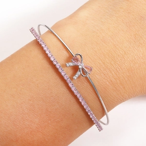 Detail of pink zircon bow cuff bracelet and sparkling tennis chain worn on wrist
