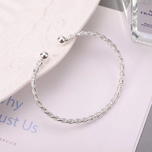 Minimalist silver twisted open bangle with polished beads on a white lifestyle background