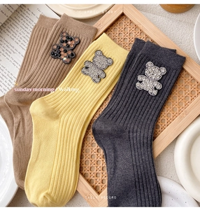 Detailed view of three-color crew socks featuring rhinestone bear decor on rib-knit cotton