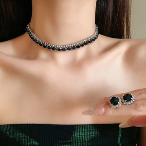 Detail shot of elegant black pearl floral necklace and stud earrings set on a model