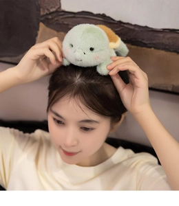 Close-up of a cute plush green turtle hair accessory worn by a female model at home