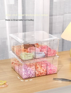 Macro view of a double-layer clear acrylic bead organizer box on a wooden desk surface