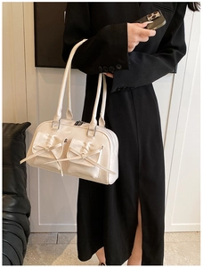 Détail du sac blanc brillant avec deux poches avant ornées de nœuds délicats décoratifs