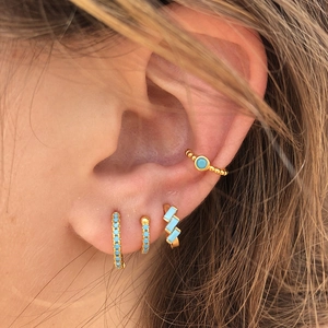 Close-up of bohemian gold earring set featuring turquoise stones on a woman's ear