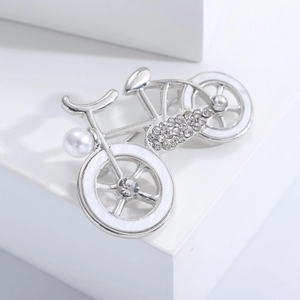 Detail of silver bicycle brooch with faux pearl, crystals and white enamel finish