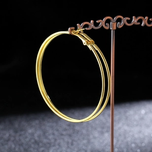 Detailed view of large thin gold-plated hoop earrings hanging on a vintage jewelry stand