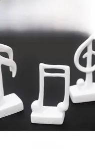 Detail view showing textured white resin music note sculptures with minimalist rectangular bases