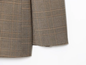 Gros plan sur la texture du tissu à carreaux marron et gris de la manche du costume