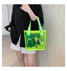 Detailed view of neon green transparent PVC tote bag with black butterfly prints on a model