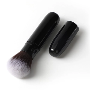Detail of retractable makeup brush with black glossy cap and soft gradient bristles