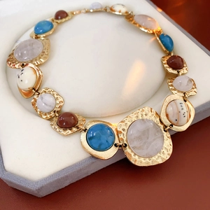 Detail of vintage golden hammered bracelet with irregular blue and brown gemstones