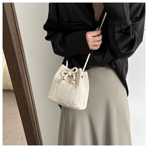 Close-up of cream woven bucket bag featuring herringbone pattern and drawstring detail