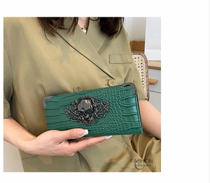 Detail of green crocodile texture clutch with gothic metal skull decoration