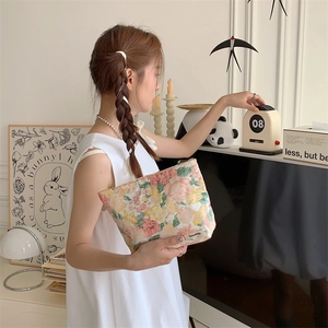 Detailed close-up of a floral cotton makeup bag held in a cozy interior setting