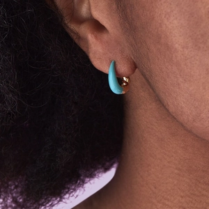 Close-up of a gold U-shaped twisted croissant hoop earring with turquoise enamel on ear