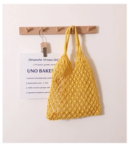 Detail of a bright yellow hand-woven cotton net beach bag with hollow texture