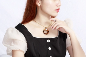 Close-up of golden necklace with tortoise shell ring pendant and clear crystal detail
