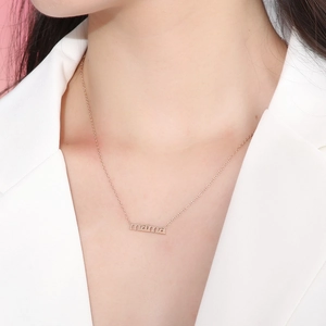 Close-up of rose gold mama letter pendant necklace worn on a woman's collarbone