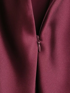 Detail of invisible zipper closure on wine red satin midi dress with smooth texture