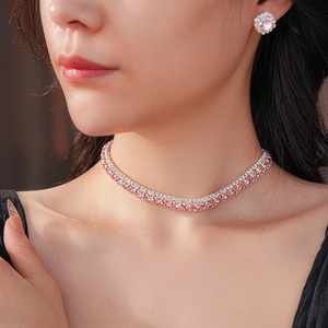 Close-up of elegant pink sparkling diamond necklace and stud earring set on model