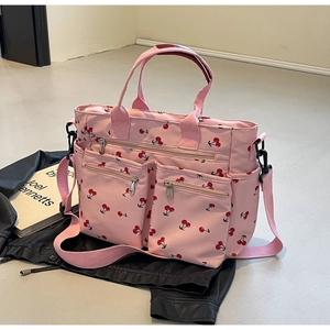Close-up of pink cherry print tote bag with multiple zipper pockets and nylon texture
